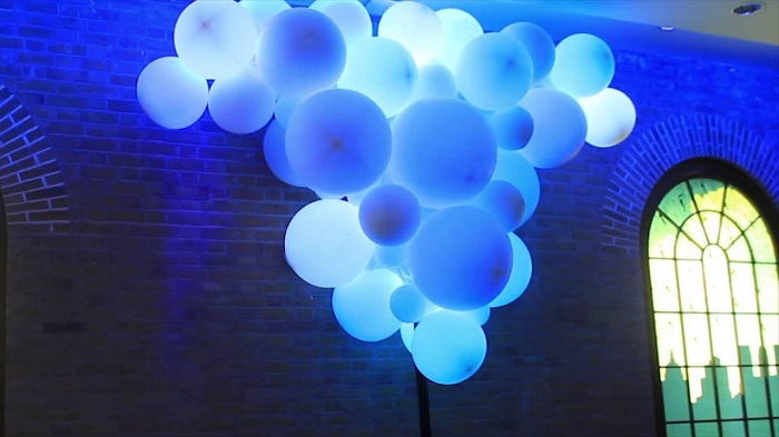 White Balloons In Blue Lightings Floating In Air.