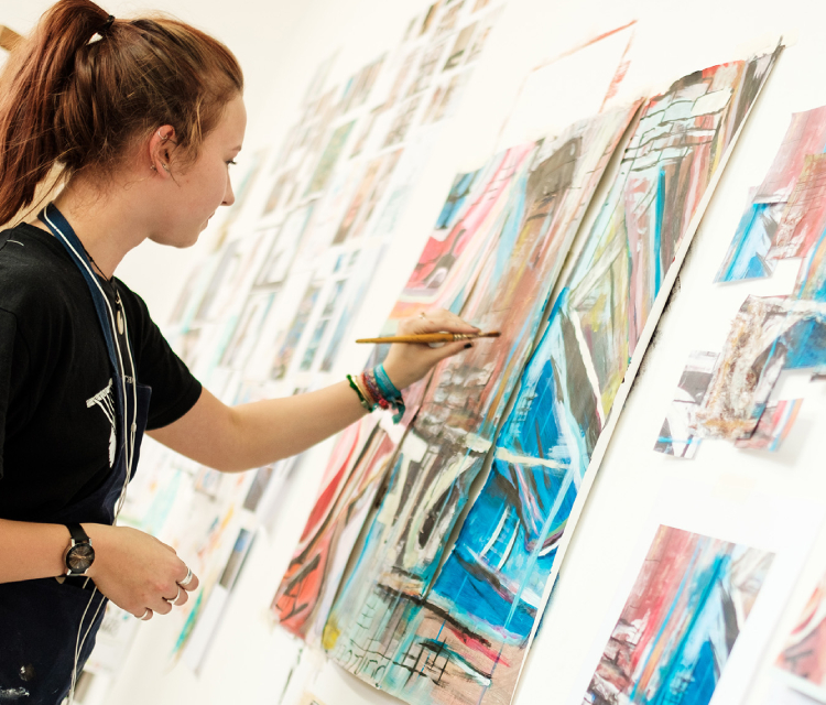 A student doing some artwork on a canvas